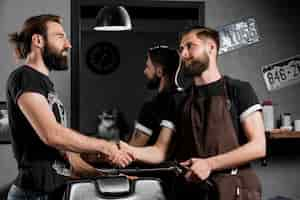 Photo gratuite coiffeur masculin se serrant la main avec le client dans le barber hop