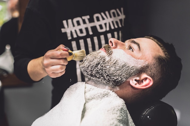 Photo gratuite coiffeur méconnaissable mettant de la mousse sur le client