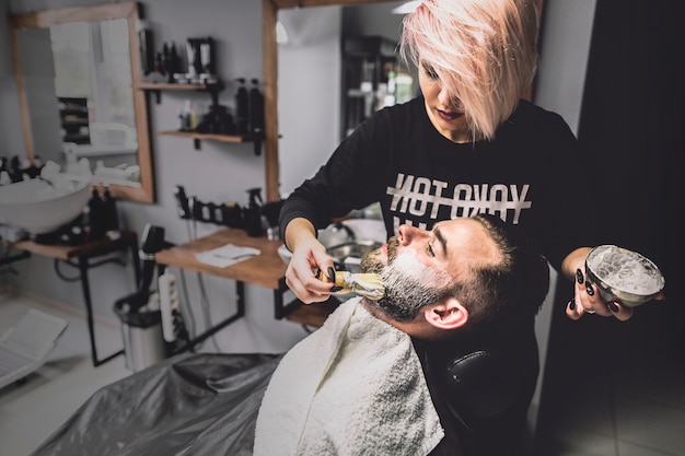 Photo gratuite coiffeur mettant de la mousse sur le visage du client