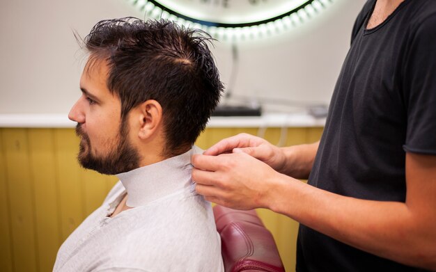 Le coiffeur prépare le client pour une coupe de cheveux