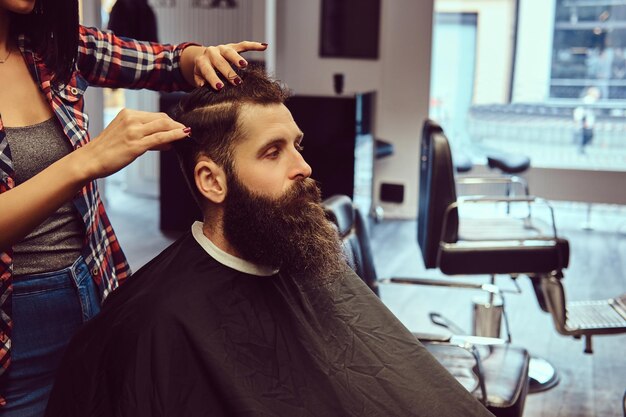 Coiffeur professionnel faisant la coiffure avec un peigne dans un salon de coiffure.