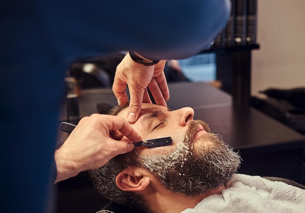 Coiffeur professionnel modelant la barbe au salon de coiffure. Photo en gros plan.