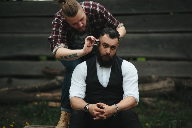 Le coiffeur rase un homme barbu dans une atmosphère vintage