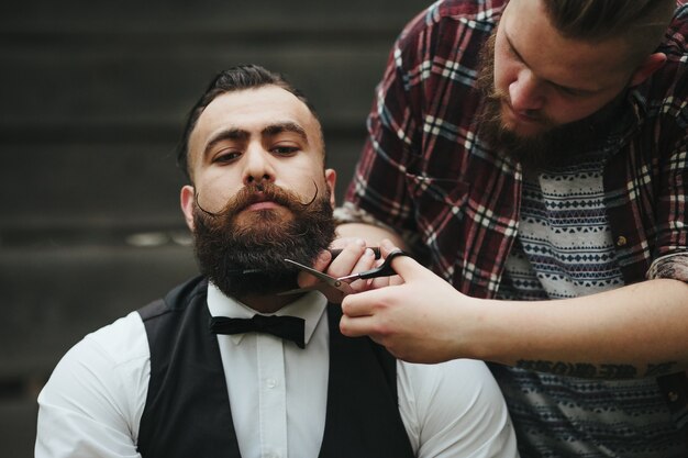 Le coiffeur rase un homme barbu dans une atmosphère vintage