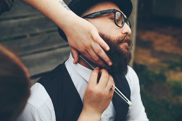 Le coiffeur rase un homme barbu dans une atmosphère vintage