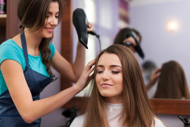 Coiffeur séchant les cheveux de la femme