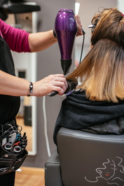 Coiffeur séchant les cheveux de la femme