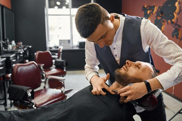 Coiffeur utilisant un rasoir pour raser la barbe d'un client caucasien