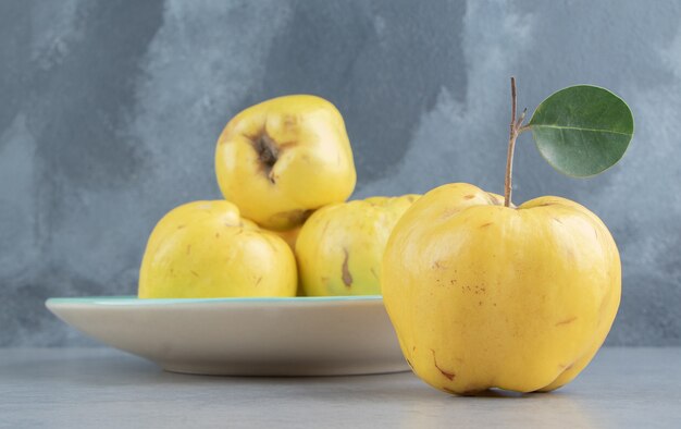 Coings sur et à côté d'un plateau sur marbre