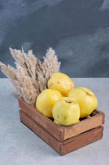 Coings entiers et moitié bio mûrs frais dans un panier en bois.