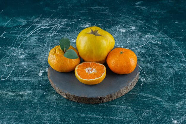 Coings et oranges sur une planche , sur la table en marbre.