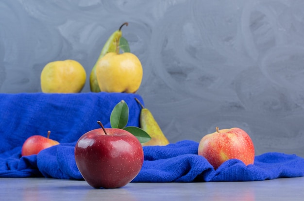 Coings, pommes et poires sur nappe bleue sur fond de marbre.