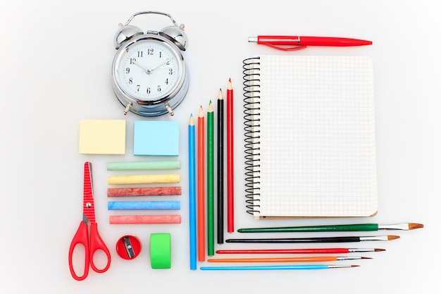 École avec cahiers, crayons, pinceau, ciseaux et pomme sur blanc