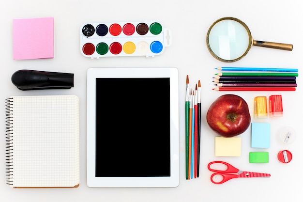 École avec cahiers, crayons, pinceau, ciseaux et pomme sur blanc