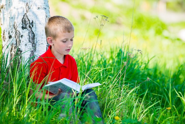 Écolier lisant le livre dans la nature