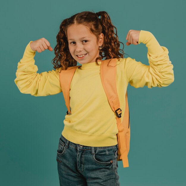 Écolière avec chemise jaune montrant les muscles