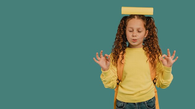 Écolière avec chemise jaune tenant un livre sur l'espace de copie de tête