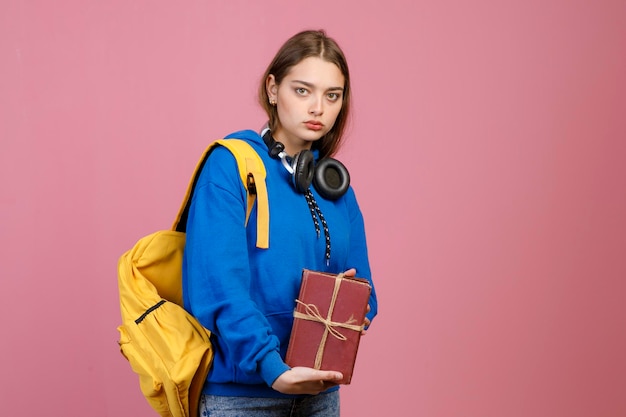 Écolière en colère debout tenant un tas de vieux livres