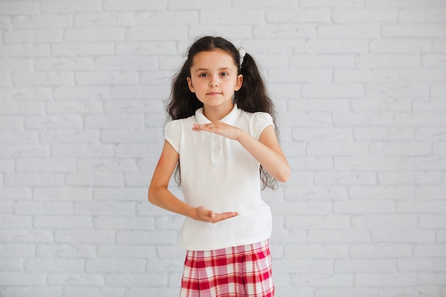 Écolière debout contre la pose de brickwall