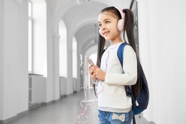 Écolière positive et intelligente écoutant de la musique