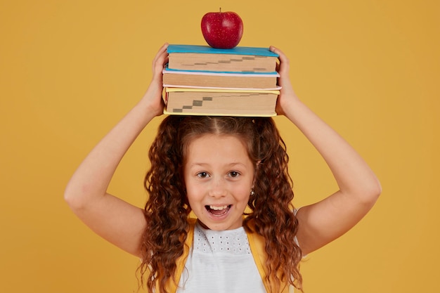 Écolière tenant des livres et pomme sur sa tête