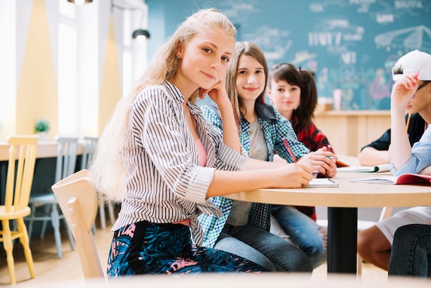 Écolières joyeuses assises sur le bureau