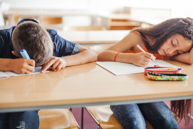 Écoliers appuyés sur la table en sommeil