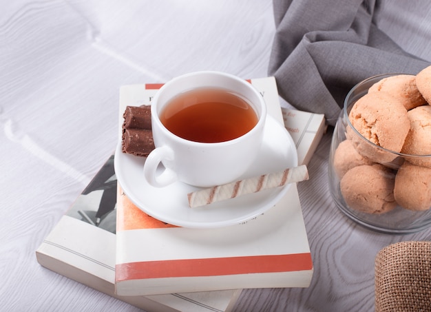 Collations sucrées, tasse de thé et chocolat et livre