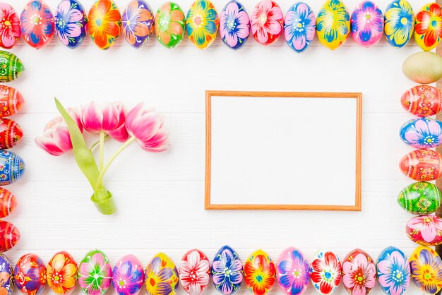 Collection d&#39;oeufs colorés sur les bords, le cadre et les fleurs