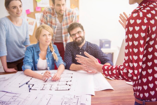 Collègues au bureau avec des plans d'architecture et un ordinateur