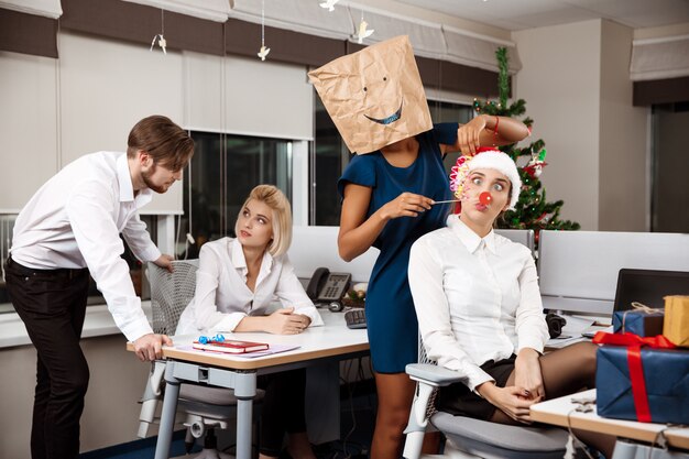 Collègues célébrant la fête de Noël au bureau en buvant du champagne en souriant.