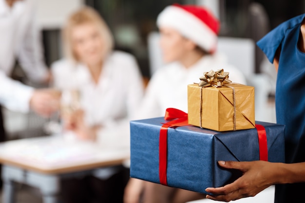 Collègues célébrant la fête de Noël au bureau en souriant donnant des cadeaux.
