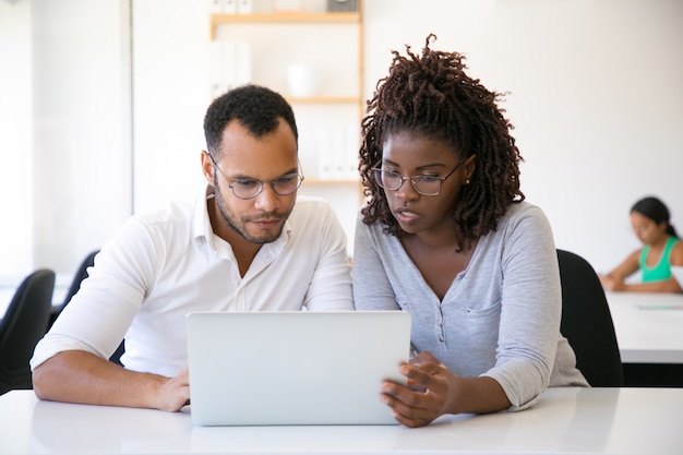 Photo gratuite des collègues concentrés et enthousiastes regardant la présentation du projet