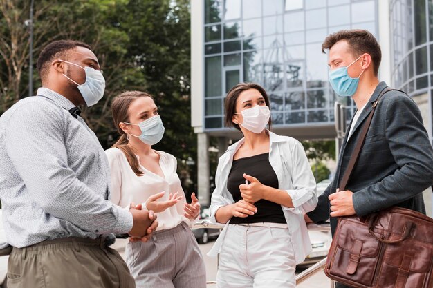 Collègues discutant à l'extérieur pendant une pandémie avec des masques faciaux