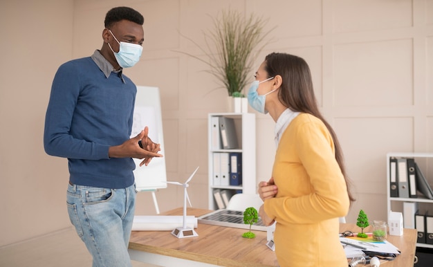 Photo gratuite collègues avec des masques travaillant ensemble au projet d'environnement