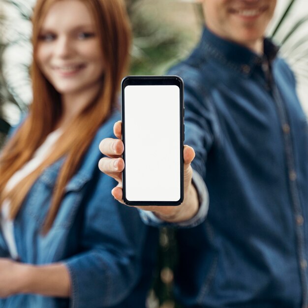 Collègues montrant un téléphone à écran vide