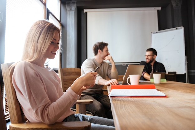 Collègues sérieux assis au bureau et utilisant des ordinateurs portables et un téléphone