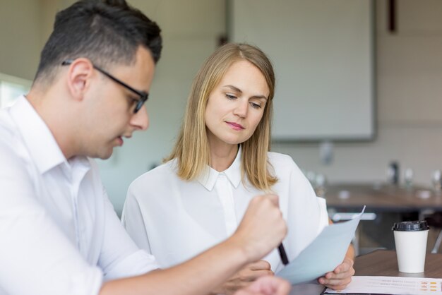 Collègues sérieux discutant des documents lors de la réunion.