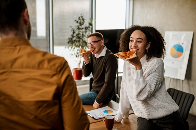 Collègues Smiley ayant une pizza lors d'une pause de réunion de bureau