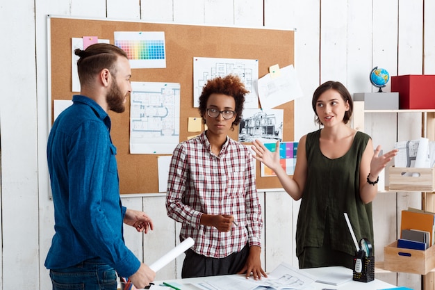 Des collègues souriant, parlant, discutant de dessins, de nouvelles idées au bureau