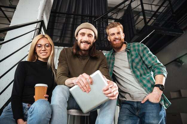 Collègues souriants au bureau à l'aide de la tablette tactile