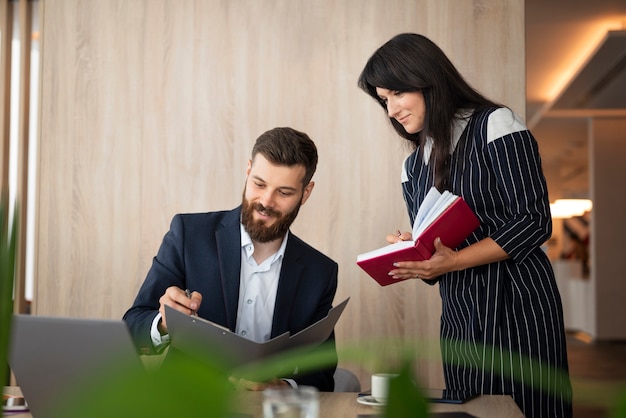 Photo gratuite collègues souriants de plan moyen au travail