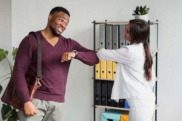 Collègues touchant les coudes au travail pendant une pandémie pour garder la distance