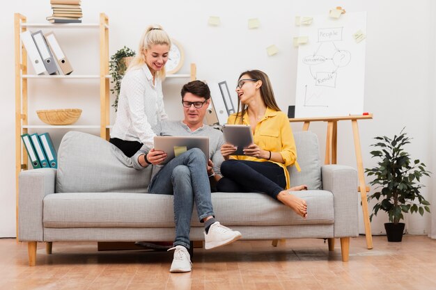 Collègues de travail assis sur un canapé et travaillant sur un ordinateur portable