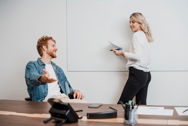 Collègues de travail parlant et écrivant sur un tableau blanc