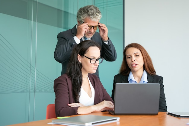 Collègues de travail regardant la présentation du projet sur ordinateur, regardant l'affichage de l'ordinateur portable