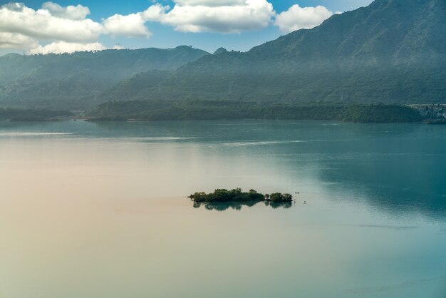 Collines couvertes de verdure entourées par la mer sous la lumière du soleil et un ciel nuageux