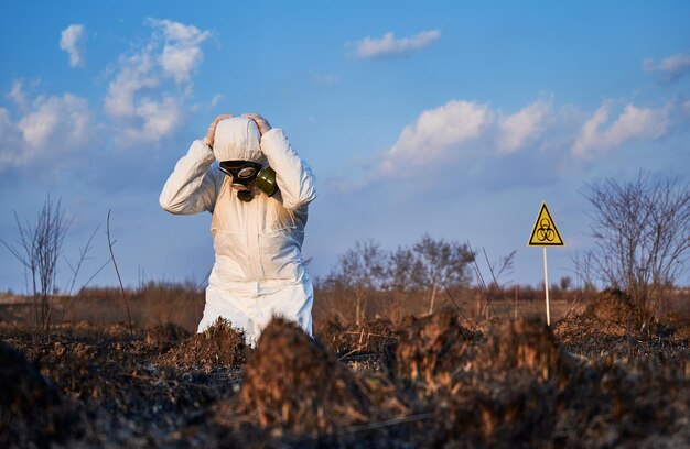 Écologiste debout sur ses genoux dans le champ avec de l'herbe brûlée