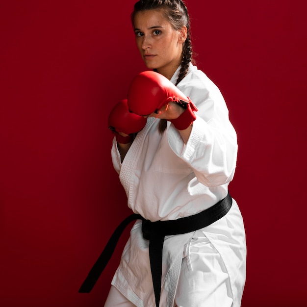 Combattant de fille avec des gants de boxe sur fond rouge