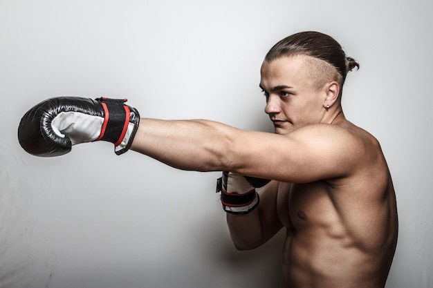 Combattant musclé dans des gants de boxe sur fond blanc